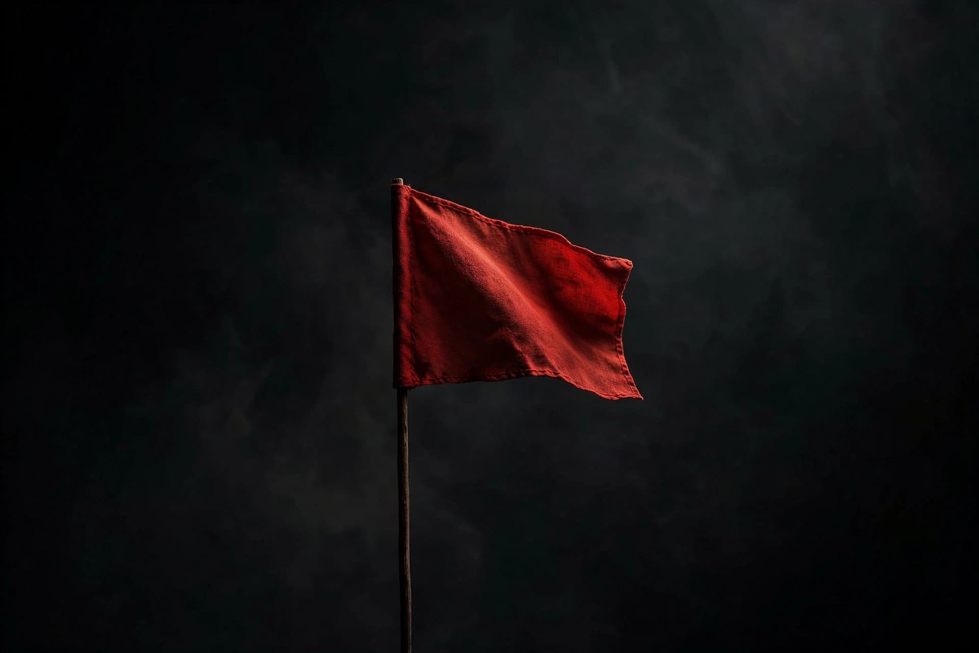 Single small red flag on a pole against a dark minimal background